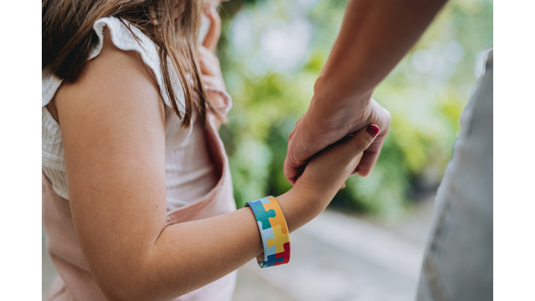 Autistic child holding hands with his mother