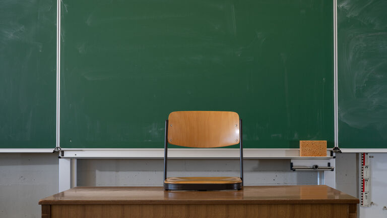 School classroom background - Empty classroom with school blackboard, teacher's desk and raised chair