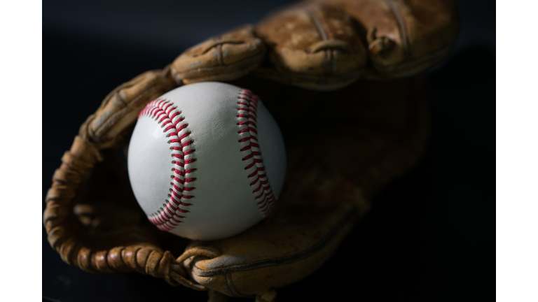 Baseball in a glove on black background.