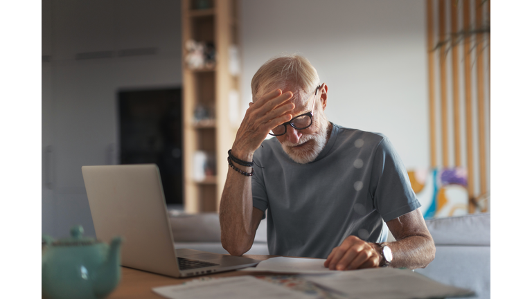 Senior man reading touching letter from friend, notification about increased healthcare costs, bad medical test results, hight utility bill. Elderly man feeling anxious, sad and sentiment.