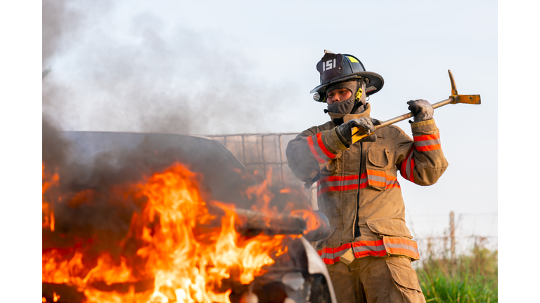 Firefighters rescue victim inside burned car.