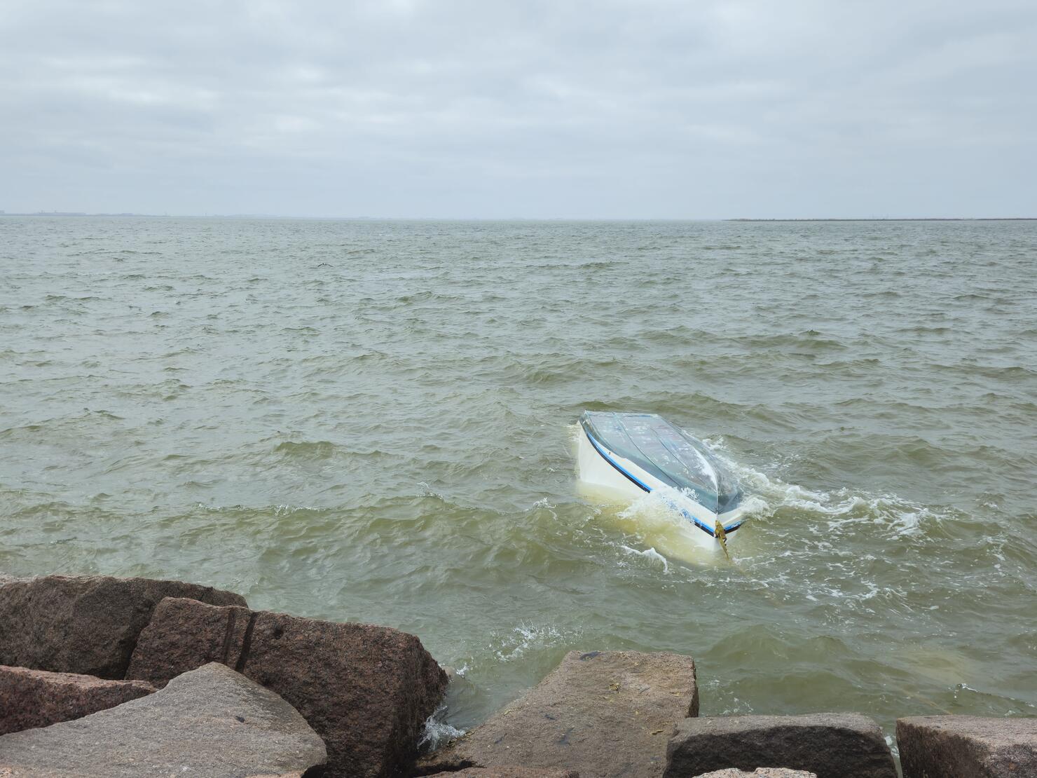 Capsized Boat Near Rocky Coastline