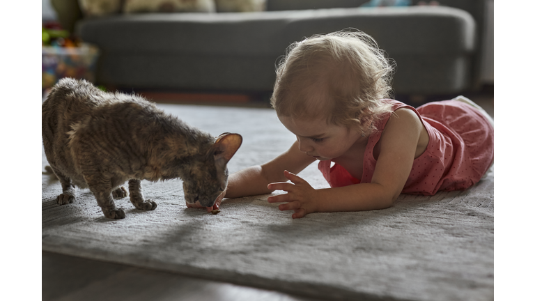Cute girl with cat on the floor at home