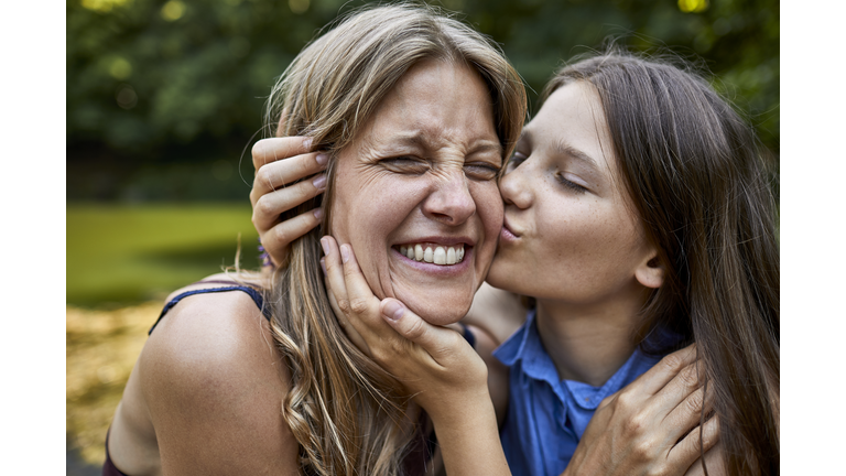 Girl hugging and kissing happy mother