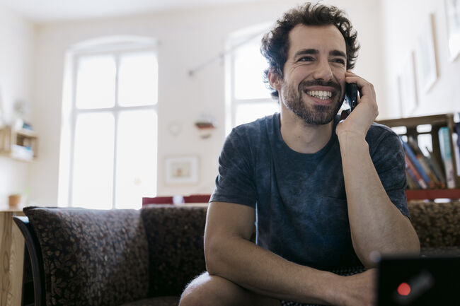 Man Smiling While Talking On Smartphone To Someone