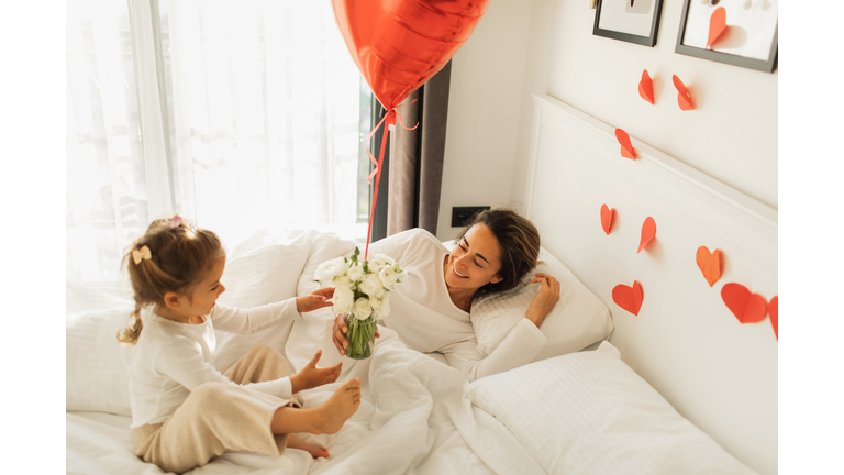 Little Daughter wakes up mother and Giving Gifts for her in Bed.