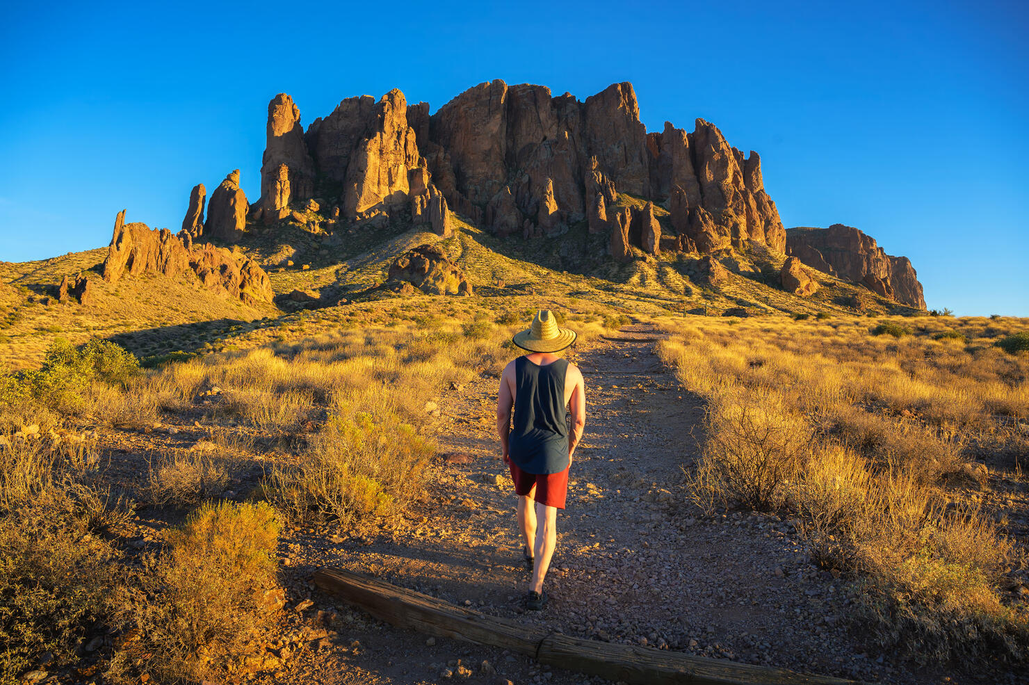 Hiker walks towards Superstition Mountains in Lost Dutchman State Park, Arizona