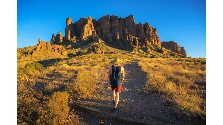 Hiker walks towards Superstition Mountains in Lost Dutchman State Park, Arizona