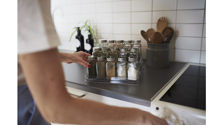 Woman's hands checking spices on spice rack