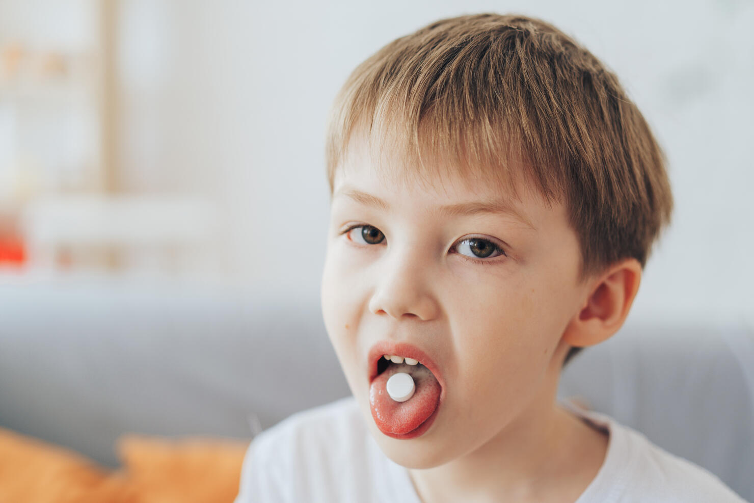 Boy holding white pill on his tongue