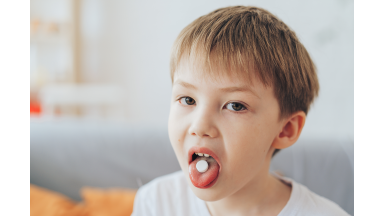 Boy holding white pill on his tongue