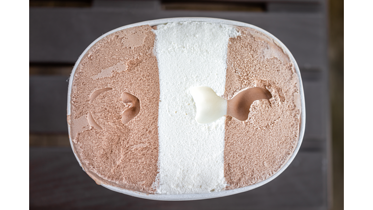 Flat top lay view of container carton of dark and milk chocolate vanilla neapolitan ice cream frozen dessert gelato storebought with texture of dairy cream three flavors