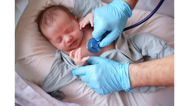 Doctor uses stethoscope to listen to baby