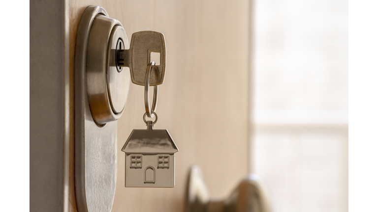 CLOSE UP OF KEY AND HOUSE KEYCHAIN ​​IN HIGH SECURITY DOOR LOCK. HOME INSURANCE CONCEPT. COPY SPACE.