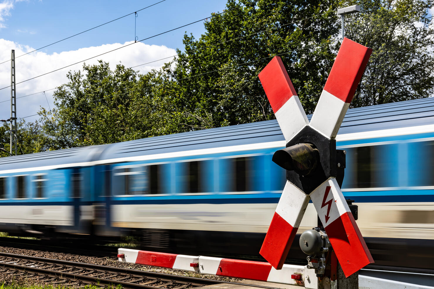 Closed barrier at a railroad crossing with fast passing passenger train