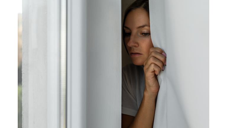 Woman scared looking through the window seeking safety