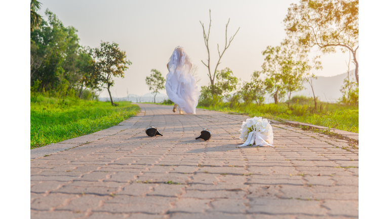 Beautiful bride wearing a white wedding dress running away alone