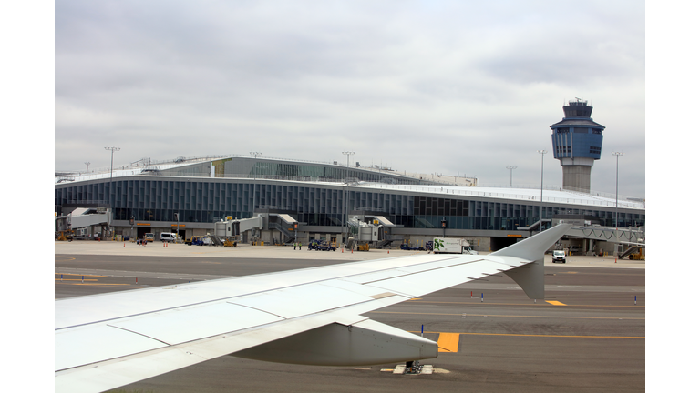 Plane landing at Laguardia airport, air traffic control tower in background - New York City, USA