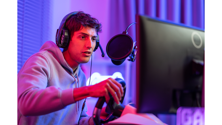 Caucasian young esport male gamer play online video game on computer. Handsome man gaming player feel happy and excited, enjoy technology broadcast live streaming while plays cyber tournament at home.