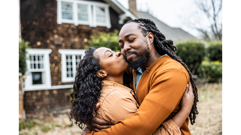 Portrait of young couple in front of their home