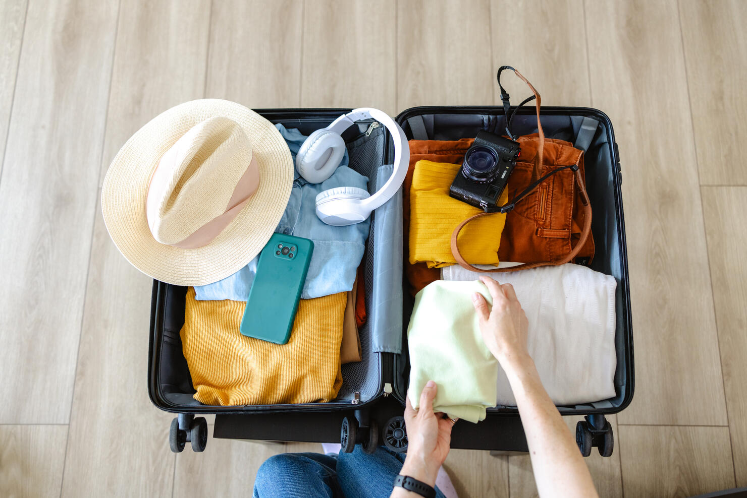 Cropped photo of an unrecognizable woman putting cloathing  in her suitcase