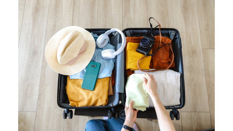 Cropped photo of an unrecognizable woman putting cloathing  in her suitcase