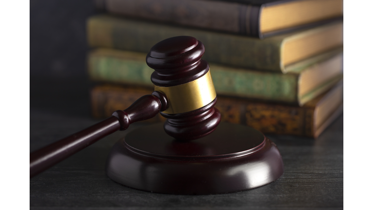 Wooden Judges Gavel on a Desk with Books in the Background