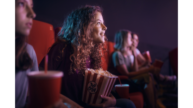 Happy little girl enjoying in movie projection at theatre.