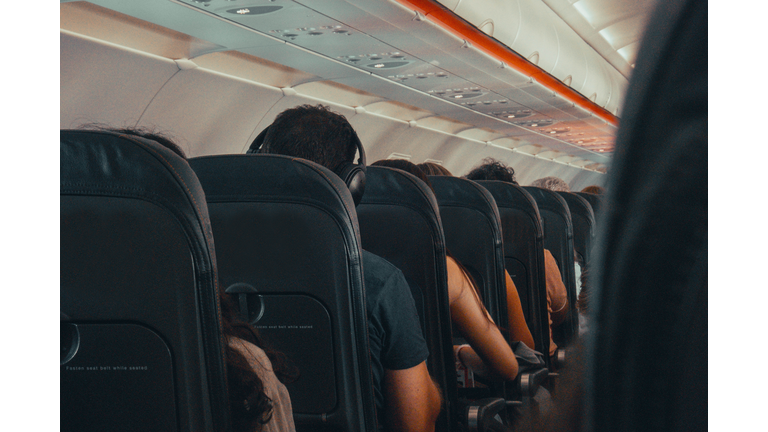 Man listening music offline with headsets in the airplane from behind