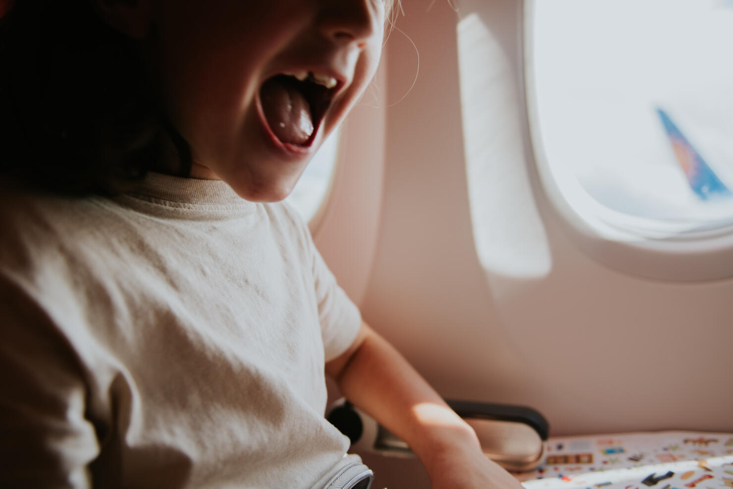 Close-up of an excited child at a window seat on a plane