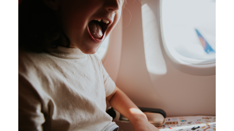 Close-up of an excited child at a window seat on a plane