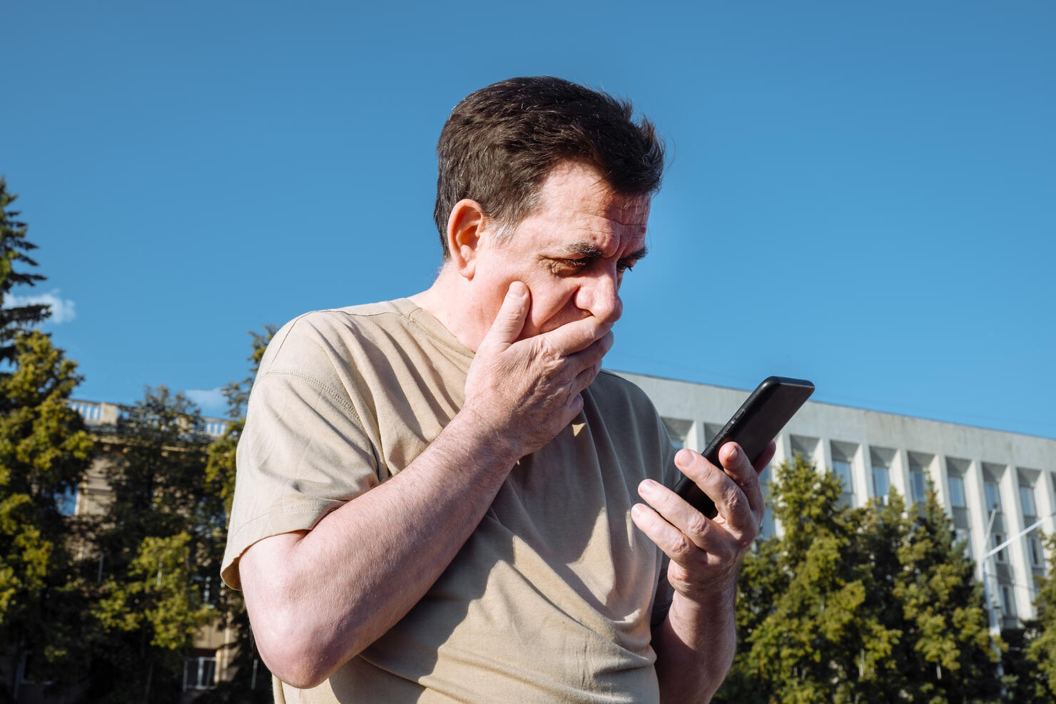 Senior man uses a phone outdoors.