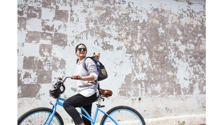 Woman on blue bike with small dog