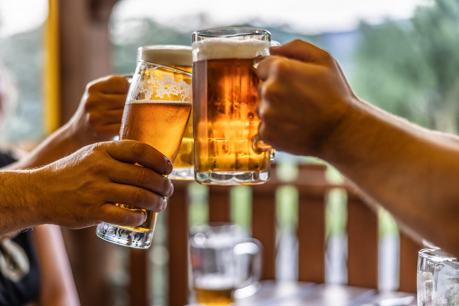 Group of friends toasting with beer on the terrace during hot summer days.