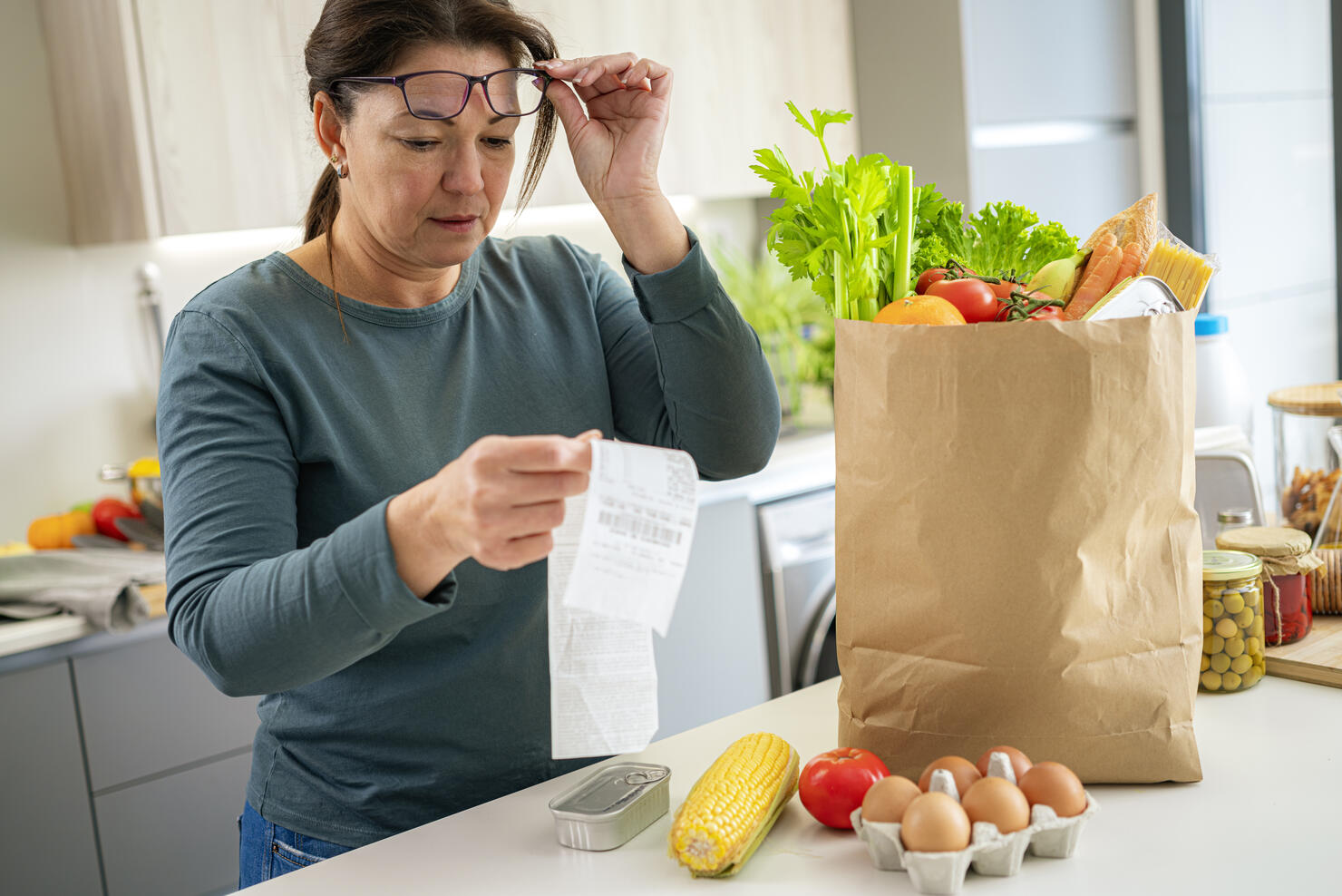 Surprised woman checking supermarket receipt after buying groceries