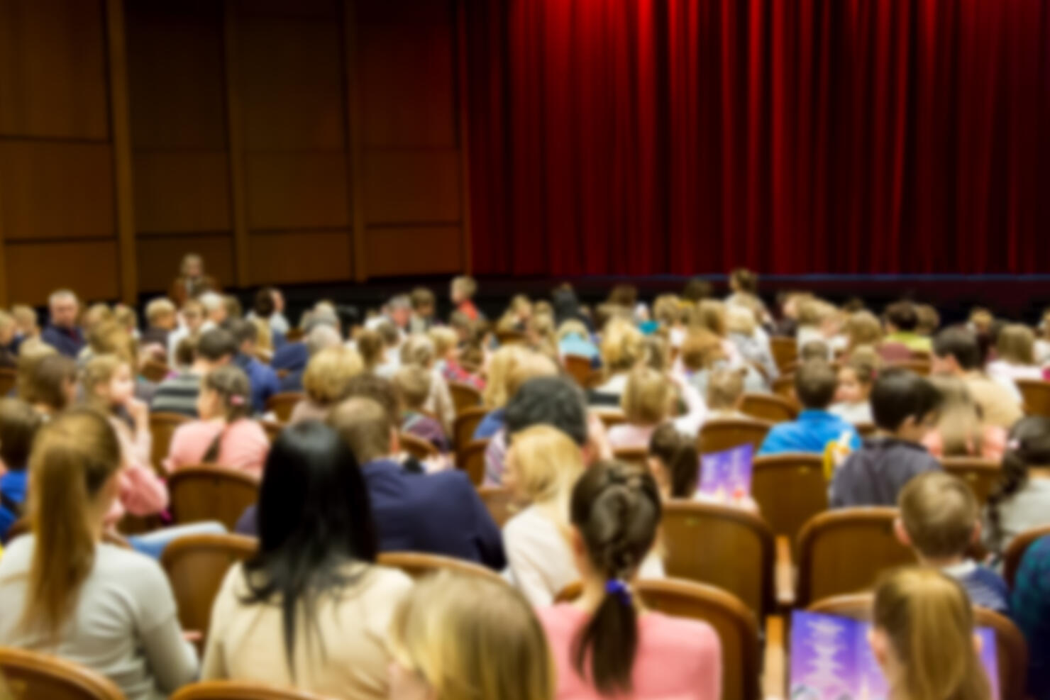 Defocused blurred image of people in the theater or cinema before the performance show.