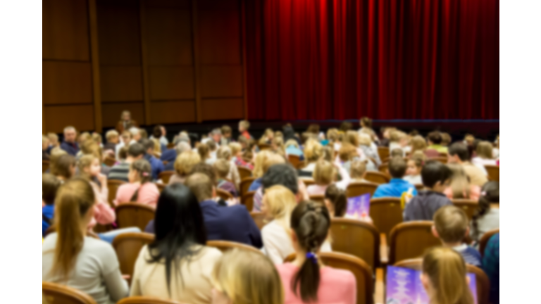 Defocused blurred image of people in the theater or cinema before the performance show.