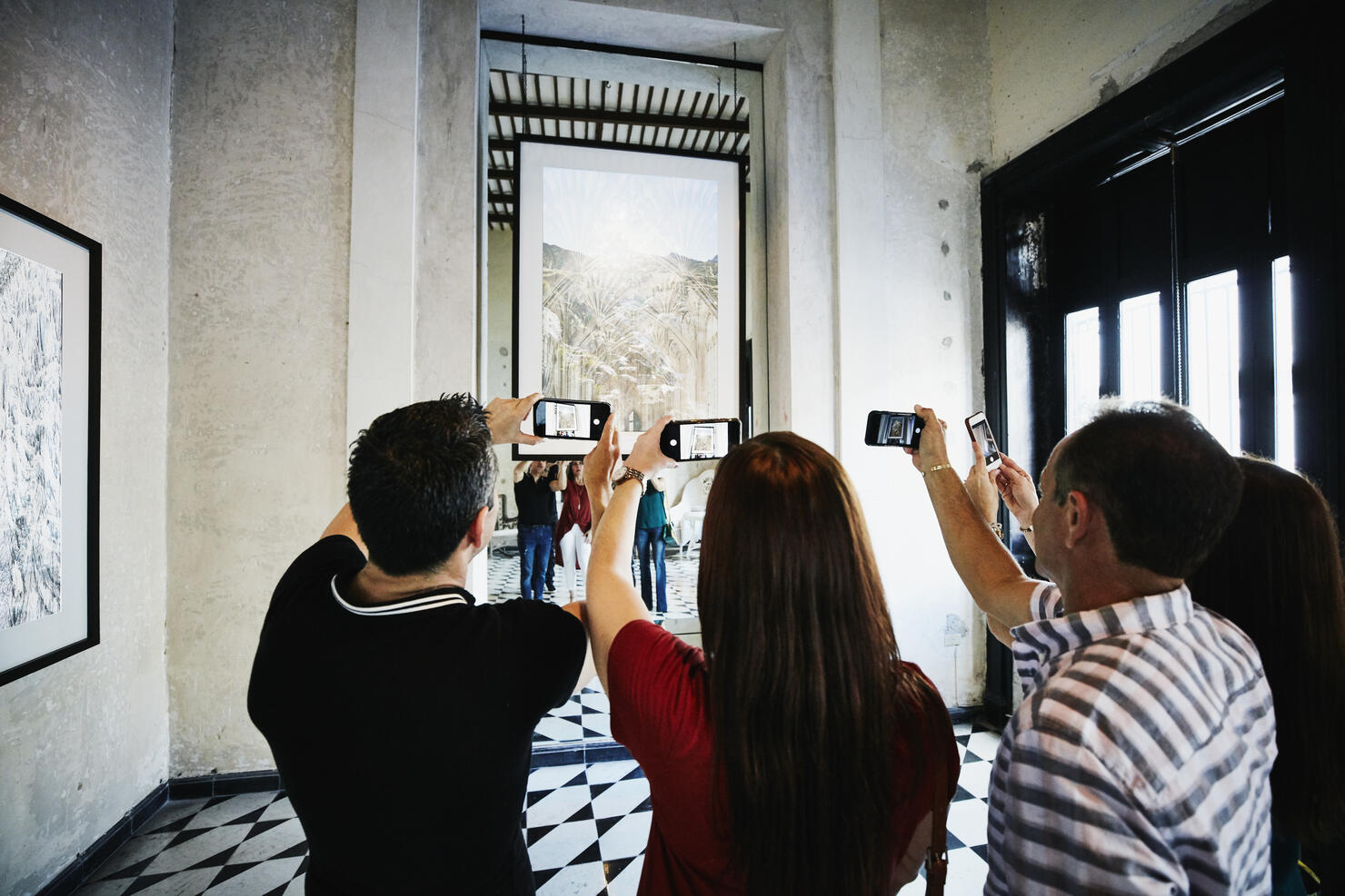People taking photos with smart phones of artwork while touring museum