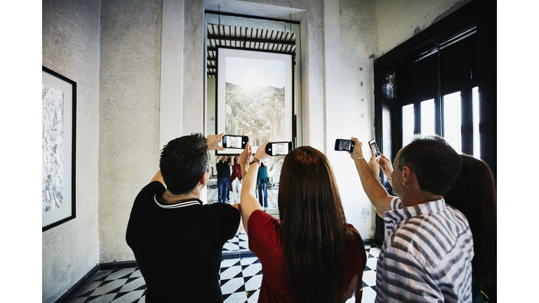 People taking photos with smart phones of artwork while touring museum