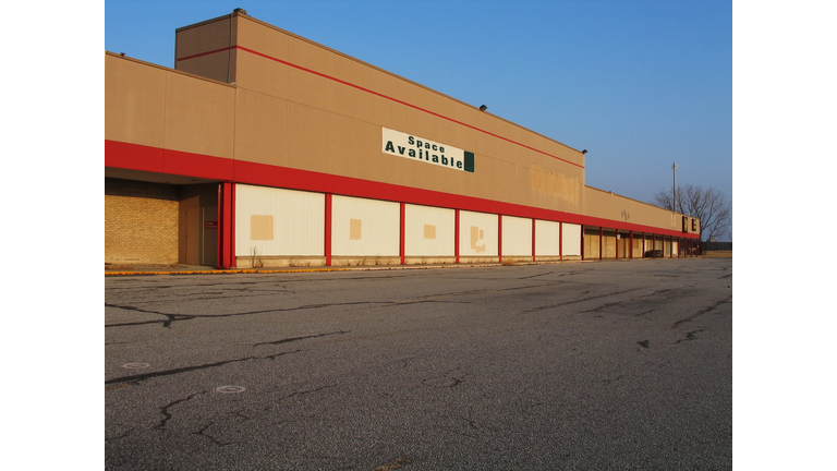 Empty building with a space available sign in front