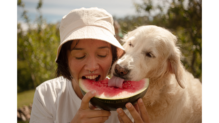 Girl eating watermelon with her dog