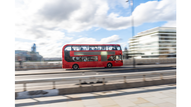 Red double-decker bus crossing london bridge on a sunny day