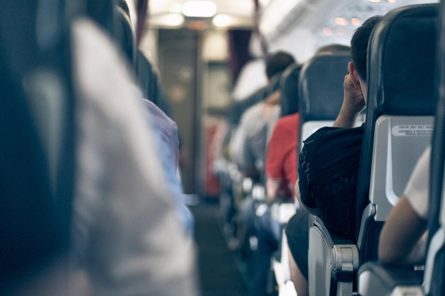 The aisle on the plane, people sitting in their seats, selective focus, lifestyle photo.
