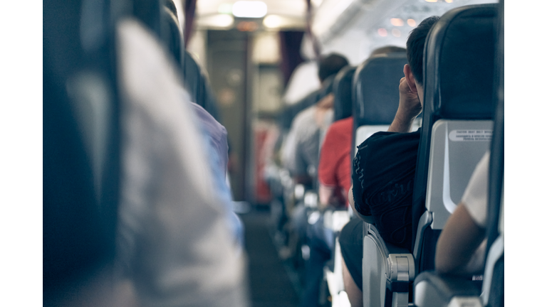 The aisle on the plane, people sitting in their seats, selective focus, lifestyle photo.