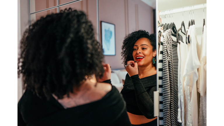 Beautiful woman putting on makeup in front of a mirror