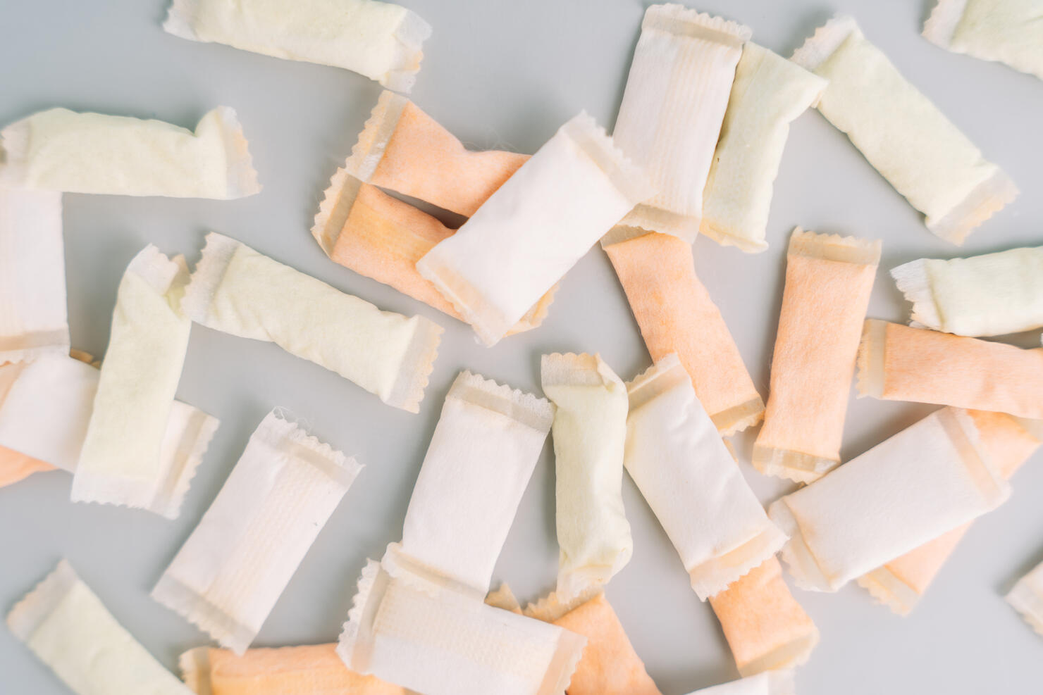 Lots of snus bags with fruit and mint flavors on a light background