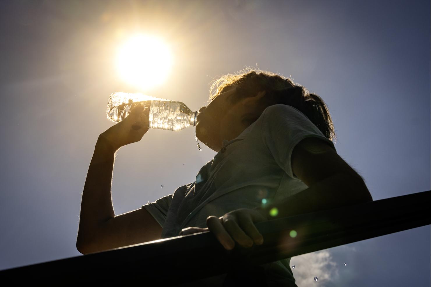 Boy drinking water from a bottle on a sunny hot day.