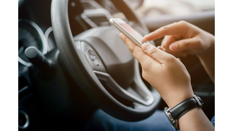 close up driver woman hand holding smartphone for using GPS navigation of travel destination and swipe for reading data on web browser or texting message online for contact while parking , journey lifestyle concept