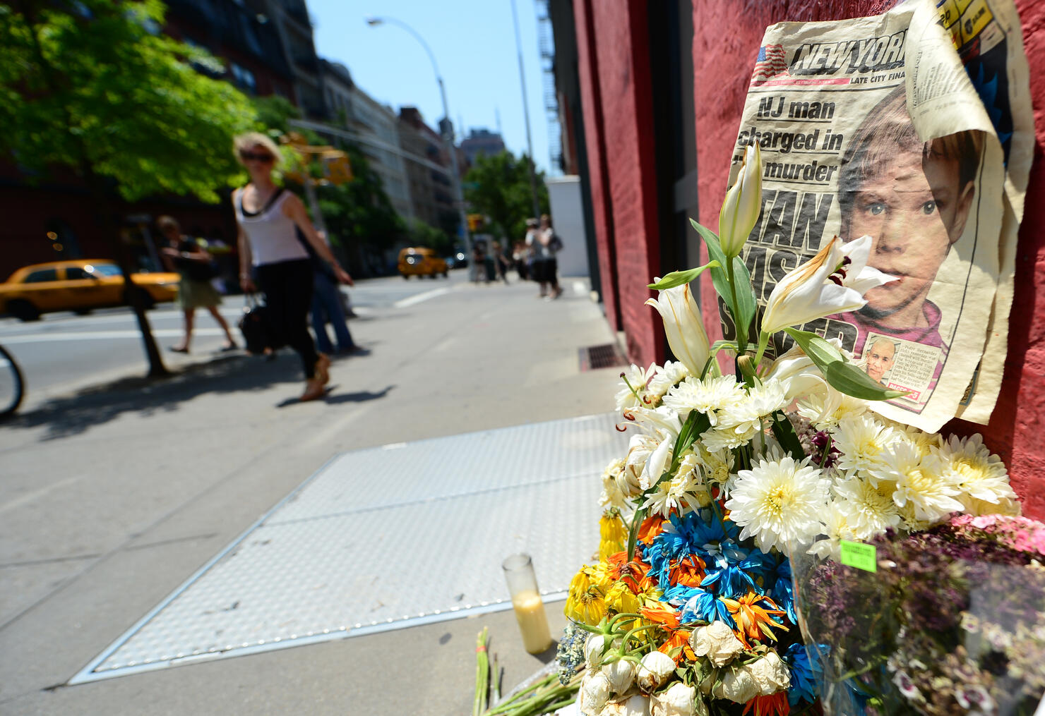 People walk past a street shrine to six-