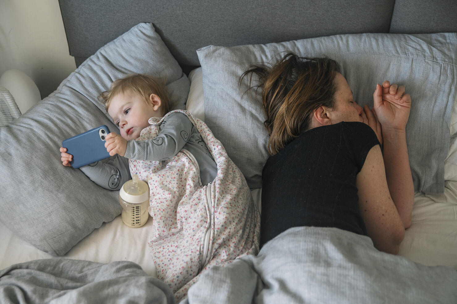 Digital Native Baby - a young baby girl uses a smartphone whilst her mum sleeps